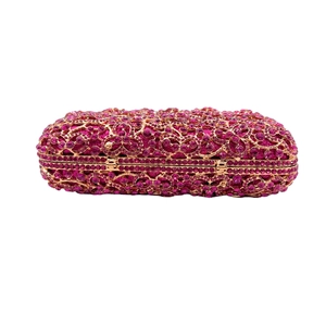 Nahaufnahme der rosérosa Strass-Clutch mit goldenen floralen Lochmustern aus Metall