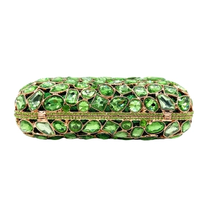 Macro detail of emerald green crystals and gold metal frame on a square evening clutch bag