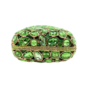 Detailed close-up of emerald green crystal stones inlaid on a gold metal clutch bag