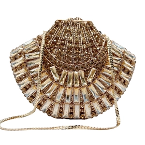Close-up of golden shell clutch bag with radiant rhinestones and thin metal chain