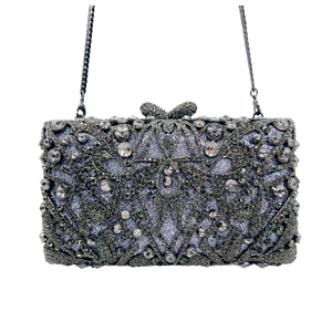 Detail of luxury rhinestone evening clutch with crystal bow clasp and silver chain strap