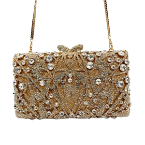 Detailed macro view of golden evening bag featuring radiating rhinestones and bow clasp