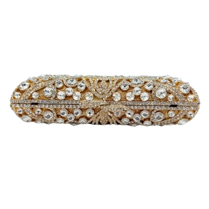 Close-up of golden pill-shaped clutch bag with intricate crystal vine patterns