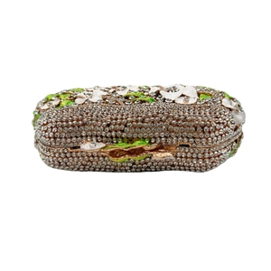 Macro detail of rhinestone evening bag with enamel flower and green leaf clasp