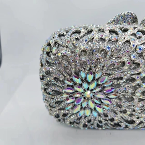 Macro shot of silver hollow-out metal clutch bag with sparkling rhinestones and crystal flower