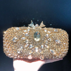 Detail of gold crystal evening clutch bag with large gemstone and bow clasp closure