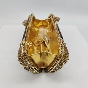 Dettaglio della pochette da sera dorata con strass e tracolla a catena a serpente