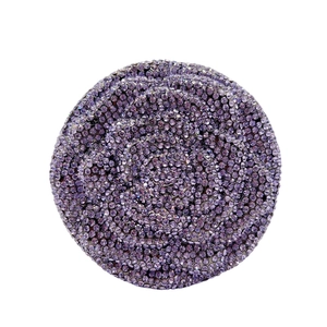 Macro shot of circular panel with spiral-set purple rhinestones on luxury clutch bag