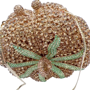 Macro di strass scintillanti e dettagli di foglie verdi su borsa da sera a zucca