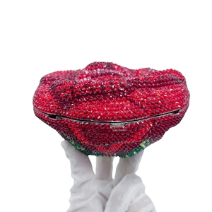Macro detail of luxury red crystal clutch bag shaped like a flower bud with green accents