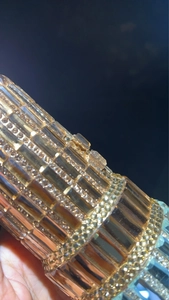 Macro view of crystal encrusted lipstick shaped evening clutch bag with gold finish