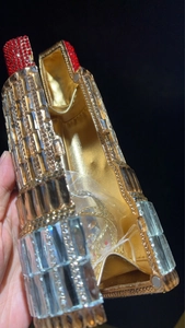 Close-up of lipstick shaped evening clutch bag with sparkling rhinestones and gold lining