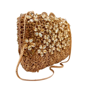 Detailed macro view of golden evening clutch featuring floral rhinestone patterns and chain