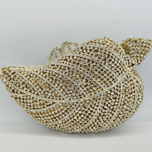 Dettaglio di una pochette dorata a forma di foglia con strass incastonati e finitura metallica
