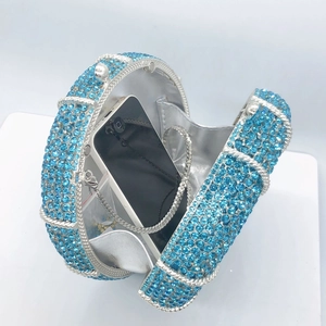 Detail view of round blue rhinestone evening bag with chain and phone for size scale