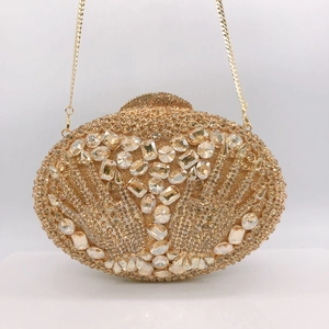 Détail d'une pochette de soirée dorée ornée de strass brillants et motif main en cristal