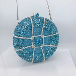 Close-up of a blue rhinestone-encrusted round evening bag with silver mesh and chain