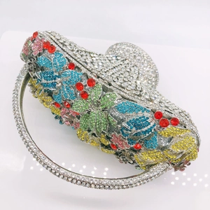 Detailed macro view of colorful rhinestone flower and cherry patterns on a luxury basket clutch