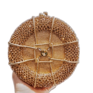 Close-up of champagne gold round clutch featuring intricate rhinestones and a large center gem