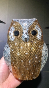 Macro detail of hand-set rhinestones and owl eye gems on an elegant evening clutch bag