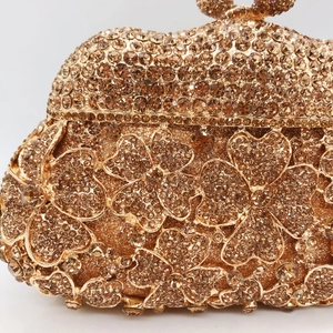 Detail of champagne gold evening clutch bag with dense rhinestones and floral pattern