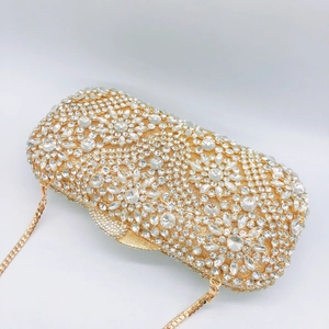 Detail of luxury gold evening clutch with intricate floral rhinestone patterns and chain