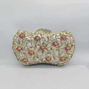 Detail of evening clutch with red rose pattern and colorful crystals on gold frame