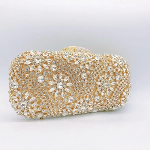 Close-up of golden evening clutch with luxury crystal floral patterns and metal clasp