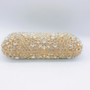Macro detail of luxury evening clutch bag featuring intricate rhinestones and gold frame