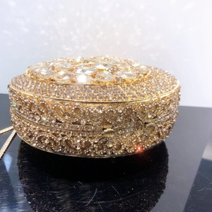 Close-up of golden hollow evening clutch with rhinestones and crystal flower clasp