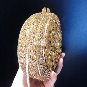 Macro side view of golden round evening clutch with sparkling crystals and metal chain