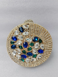 Close-up of golden clutch bag featuring intricate crystal pavé and colorful gemstones