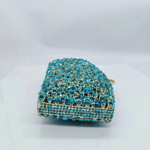 Close-up of luxury evening clutch bag featuring sky blue rhinestones and gold metal frame