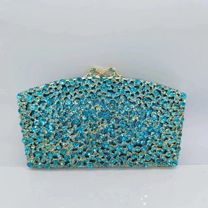 Detailed close-up of blue crystal evening clutch bag with golden bow clasp