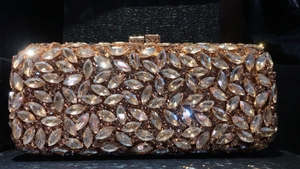 Détail macro des strass marquise sur une pochette de soirée en métal or rose