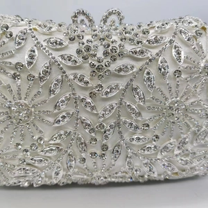 Gros plan détaillé des motifs floraux en strass sur une pochette de soirée en satin blanc