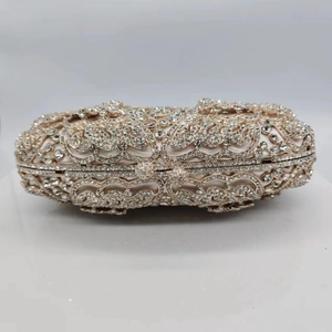 Detail of golden evening clutch featuring hollow butterfly metalwork and crystal embellishments