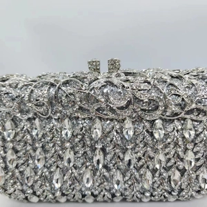 Macro detail of silver clutch bag featuring hollow flower weaving and crystal rhinestones