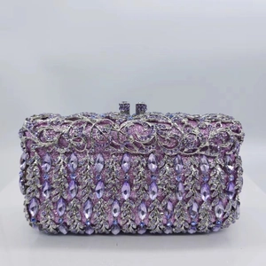 Detail of purple rhinestone clutch with silver hollow floral patterns and crystal clasp