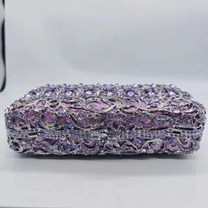 Detail of silver hollow floral metal frame with purple crystals on luxury clutch bag