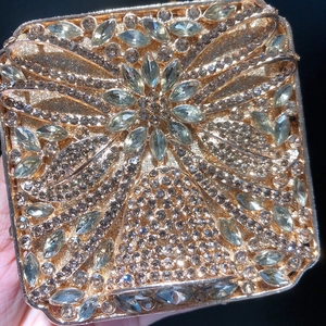 Luxurious gold square evening clutch with radiant floral crystal patterns on black background