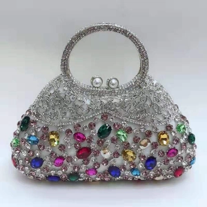Close-up of crystal clutch bag with colorful oval gemstones and pearl clasp