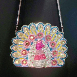 Detail of peacock evening clutch bag with colorful rhinestones and silver metal chain