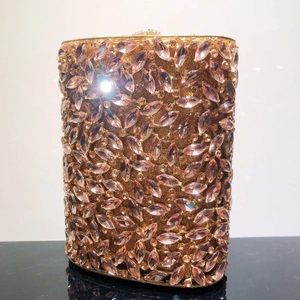 Detailaufnahme der luxuriösen champagnergoldenen Clutch mit rosa Kristallen