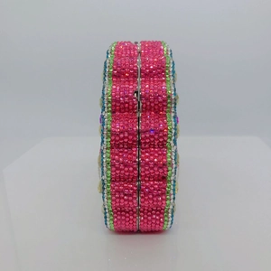 Macro detail of the crystal encrusted pink clutch bag showing side metal frame and texture