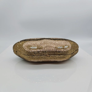 Detailed close-up of a gold evening clutch with rhinestones and metal buckle