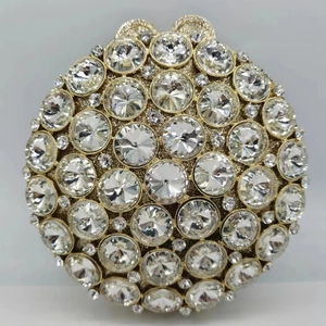 Détail d'une pochette ronde dorée avec coque en métal ornée de strass étincelants