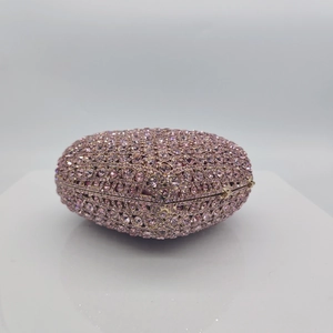 Detail of pink rhinestone heart-shaped clutch bag with luxury gold-tone metal clasp frame
