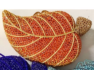 Detail of leaf-shaped evening clutch featuring orange crystals and gold leaf veins