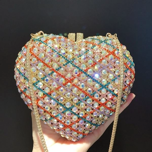 Macro view of heart-shaped clutch bag with colorful rhinestones and gold chain